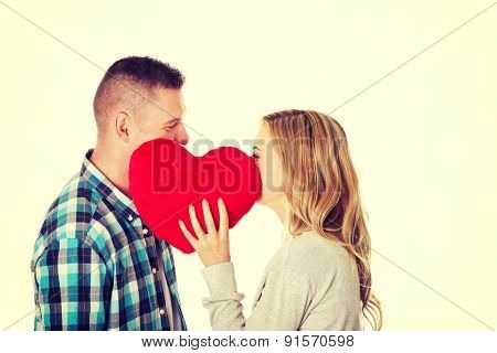 Young beautiful couple whispering behind the pillow