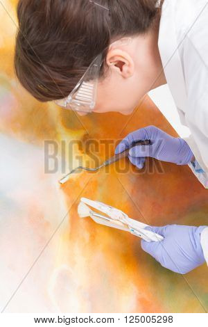 Artwork conservator at work with old painting wearing protective suit
