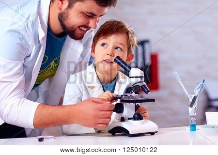 teacher helps kid to conduct experiment with microscope