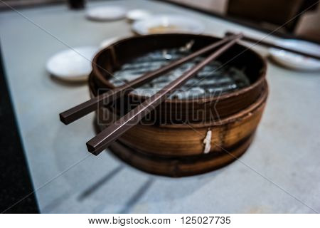 Traditional chinese food, steamed dumpling served on table in a wooden dish and with wooden chopsticks.