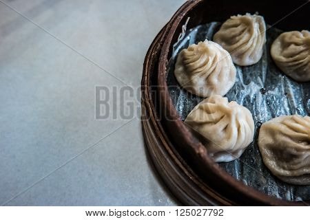 Traditional chinese food, steamed dumpling served on table in a wooden dish and with wooden chopsticks.