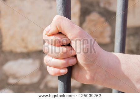 hand of woman holding the iron bar at the prison