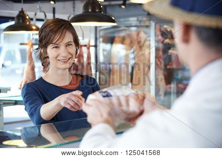 Female Customer Buying Meat In Butchers Shop