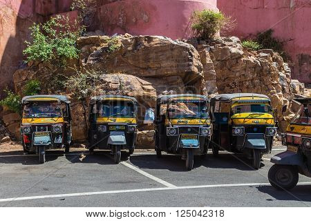 JAIPUR INDIA - 22ND MARCH 2016: Tuk Tuk Rickshaws parked outside in a rural area in Jaipur India. People can be seen.