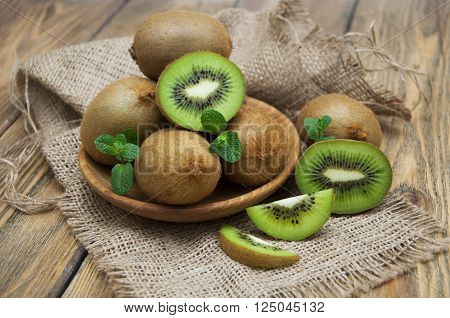 Fresh juicy ripe kiwi in a wooden plate on a wooden background