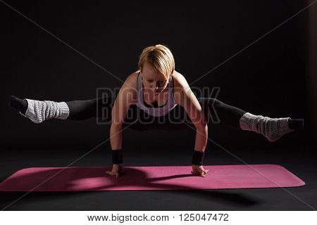 Young woman practicing yoga, Tittibhasana / Insect / Firefly Pose