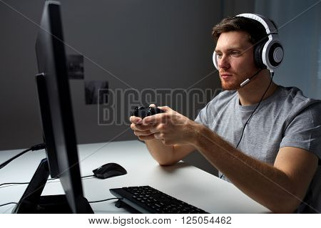 technology, gaming, entertainment, let's play and people concept - young man in headset with controller gamepad playing computer game at home and streaming playthrough or walkthrough video