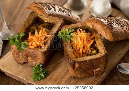 Fresh pea soup in a Bread Bowl, on a wooden board with salt and papper