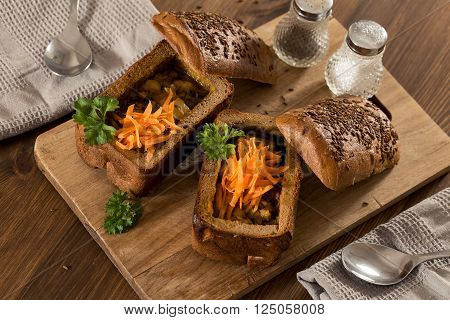 Fresh pea soup in a Bread Bowl, on a wooden board with salt and papper