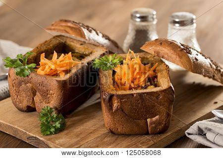 Fresh pea soup in a Bread Bowl, on a wooden board with salt and papper
