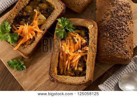 Fresh pea soup in a Bread Bowl, on a wooden board with salt and papper