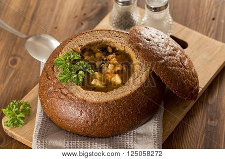 Fresh pea soup in a Bread Bowl, on a wooden board with salt and papper