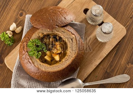 Fresh pea soup in a Bread Bowl, on a wooden board with salt and papper