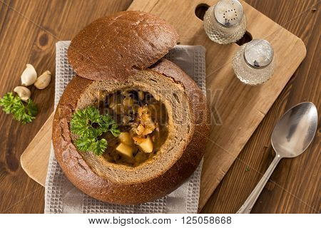 Fresh pea soup in a Bread Bowl, on a wooden board with salt and papper