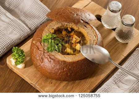 Fresh pea soup in a Bread Bowl, on a wooden board with salt and papper
