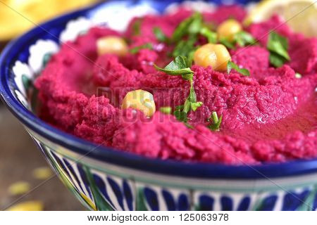 Beetroot hummus in a colorful bowll on a wooden table.