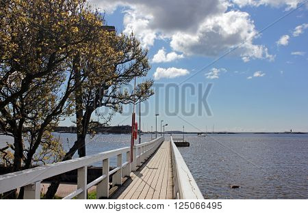 Wooden footbridge to pier at Baltic sea in spring sunny day Helsinki Finland.