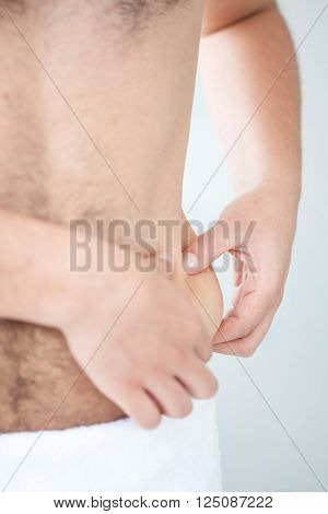 Man dressed in white showing his abdomen localized fat