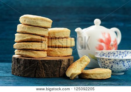 Piles of tasty round homemade cookies and teaware on deep blue background