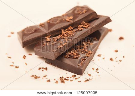 Pieces from a chocolate bar and chocolate crumbs on a white background. Close up small depth of sharpness