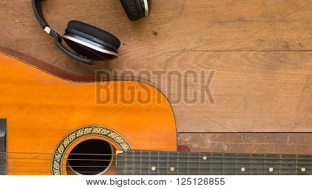 Top view workspace with headphone and acoustic guitar on wooden table background. Free space for your text.