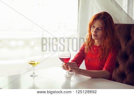 Portrait of a smiling young woman holding a glass of red wine.
