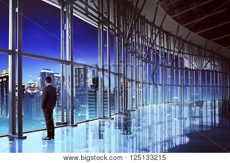 Back view of successful manager looking the city from his office