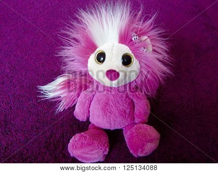 Pink plush cat toy on a soft purple carpet