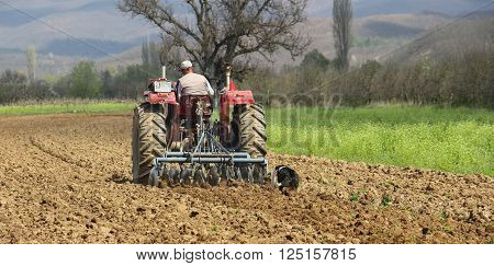pictureof a man in tractor plowing field in spring