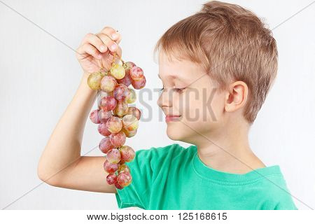 Little boy in a green shirt with a ripe grape