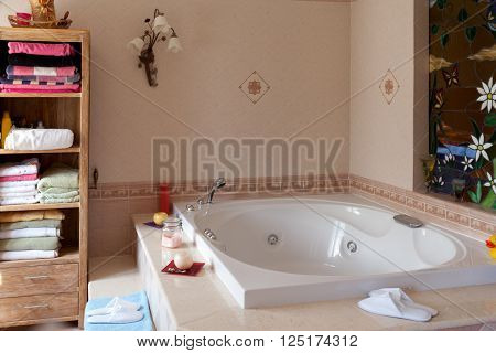 Comfortable spa-style slippers beside the  bathtub in home bathroom.