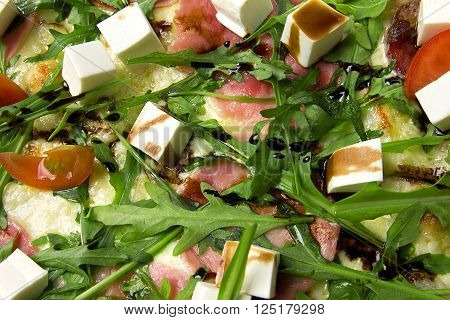 Appetizing pizza with ham, salami, arugula, cherry tomatoes, fetaksa, balsamic closeup