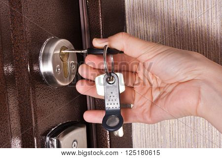 hand unlocking front door lock of house clouseup