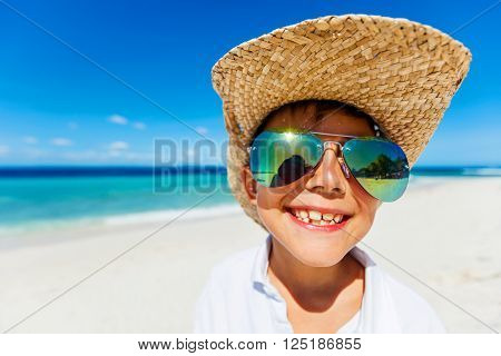 Portrait of a boy in the sunglasses and hat on the tropical white beach