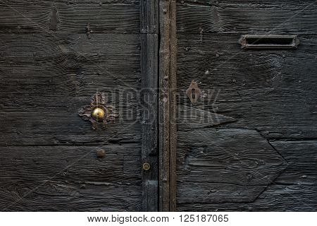 Old medieval  italian wooden door with metal handle and a mail slot