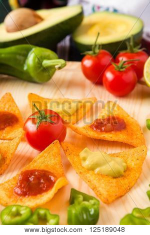 Close up of nachos chips tomato pepper and avocado over a chopping board