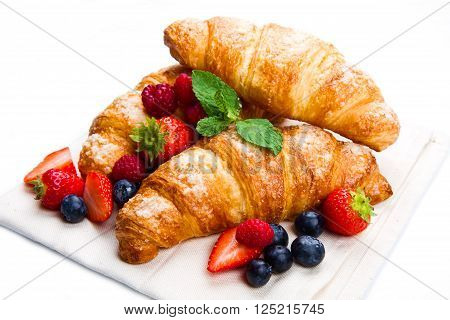 Fresh tasty croissants with berries on white background