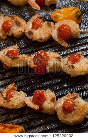 Grilled Parmesan crust shrimp with chery tomatoes on the grill with grilled mini bell peppers.
