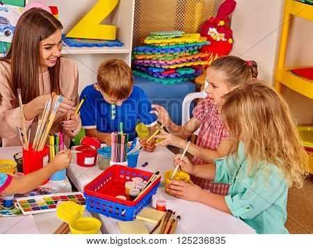 Children with teacher woman painting on paper at table  in  kindergarten .  Children paint the kids' club.