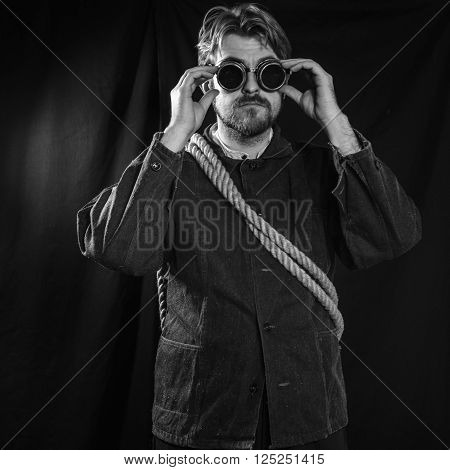 Working in a black robe corrects welding goggles . black background