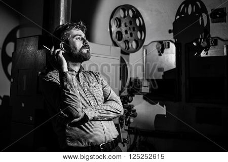 beautiful hipster man standing near a film projector in the room projectionist