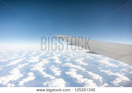 airplane wing above the clouds blue sky