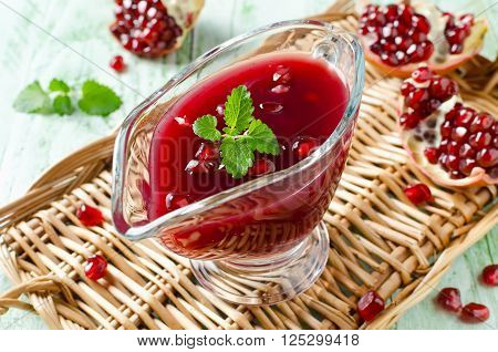 Fresh pomegranate sauce for meat on a wooden table. Sauce made from red wine and pomegranate juice