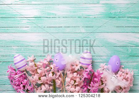 Easter or spring background. Decorative violet eggs and pink hyacinths flowers on turquoise wooden background. Selective focus. Place for text.