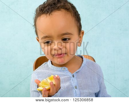 Funny toddler with a snotty nose trying to eat a lemon