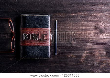 Bible, eyeglasses and pen laid on old wooden table, sign made of cookie cutters, copy space