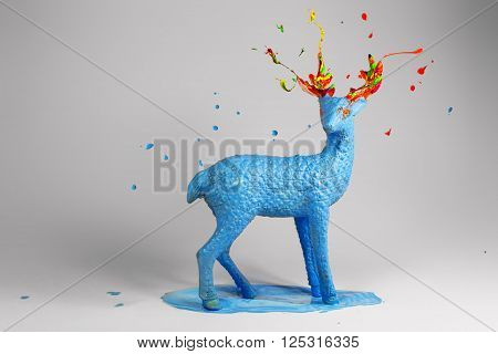 Blue deer with colorful magic horns standing in pound of blue paint