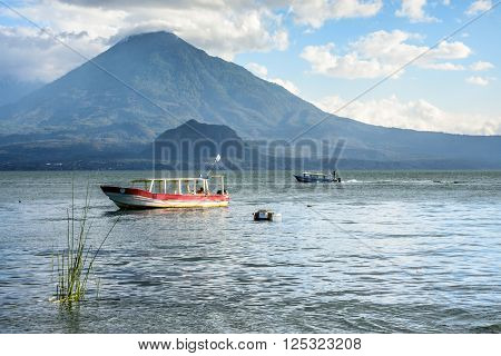 Lake Atitlan, Guatemala - April 3, 2016: Evening light on boats on Lake Atitlan with Toliman volcano behind.