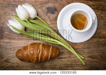 coffee, croissant and three white tulips for spring breakfast
