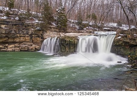 Water spills over Upper Cataract Falls a waterfall in Owen County Indiana as late winter snow melts into spring.